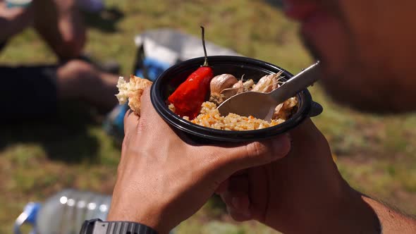 Man Eating Pilaf From a Plastic Plate in the Mountains Gaining Strength
