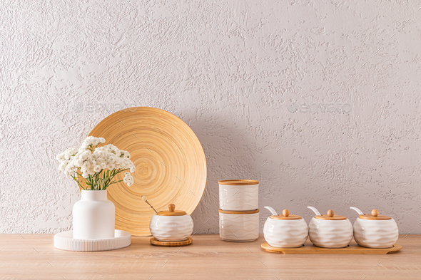 A set of white ceramic jars with bamboo lids for storing bulk products spices on a wooden countertop
