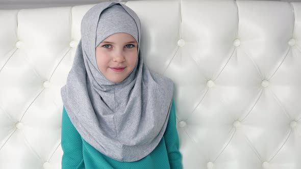 Portrait of Muslim Teen Girl in Grey Hijab is Looking in Camera alt