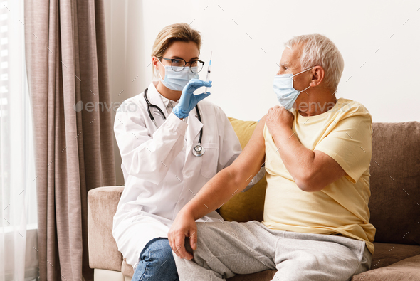 Doctor injecting vaccine to elderly man during home visit