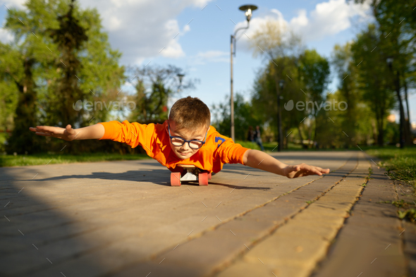 Boy lying on skateboard on his belly and riding like aviator