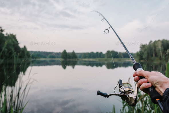 Fisherman with rod, spinning reel on the river bank. Fishing for pike,  perch, carp. Fog against Stock Photo by kurinchukolha