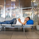 Tired Asian man sleeping flat on airport departure waiting area chairs while waiting for flight - PhotoDune Item for Sale