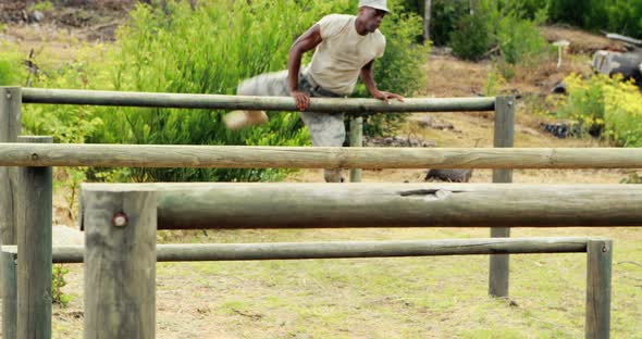 Fit man jumping over the hurdles during obstacle course alt