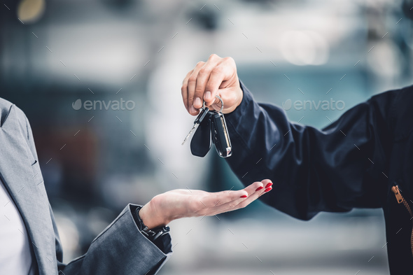 Closeup male hand giving a car key for vehicle loan credit financial, lease or rental concept