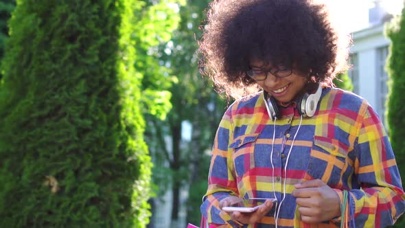 Cheerful African American Woman with an Afro Hairstyle with Packages After Shopping Uses a alt