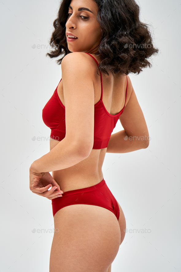Confident and middle eastern brunette woman in red bra touching