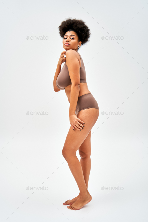 Full length of barefoot and sexy african american model in modern brown  lingerie touching shoulder Stock Photo by LightFieldStudios