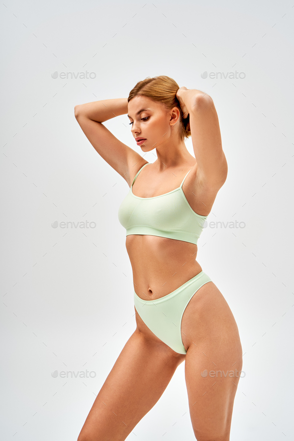 Sensual young woman with natural makeup wearing light green lingerie and  touching blonde hair Stock Photo by LightFieldStudios