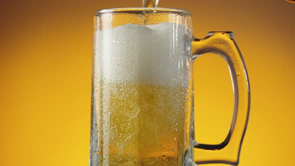 Jet of Beer is Poured Into a Wet Beer Glass with a Lot of Bubbles and Foam alt