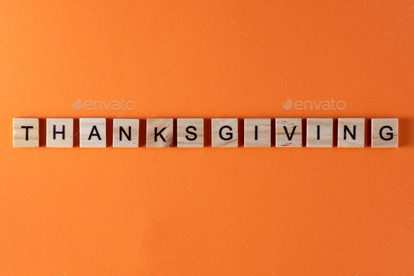 Thanksgiving word phrase in wooden letters. Motivation and slogan. Orange background