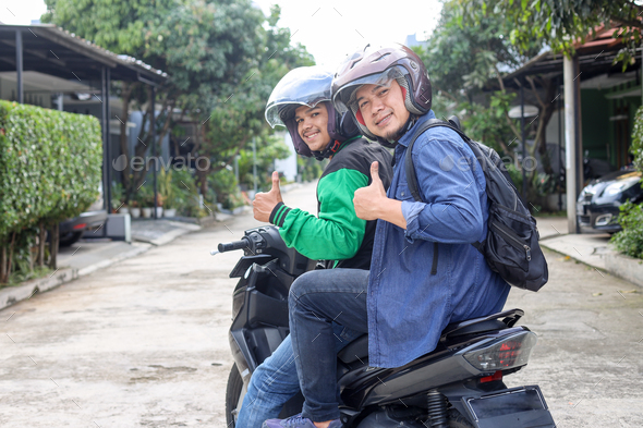 motorbike taxi driver and passenger giving thumbs up