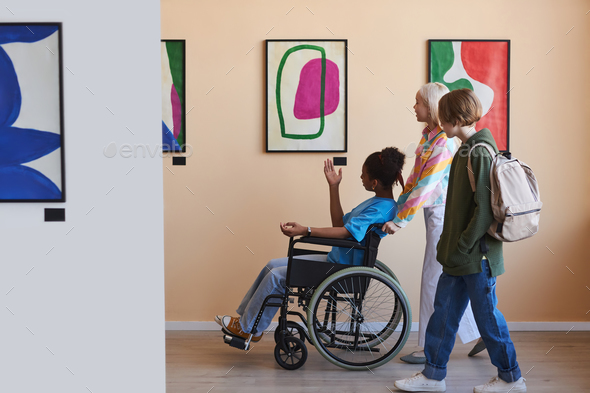 Teenagers assisting friend with disability visiting art gallery or museum