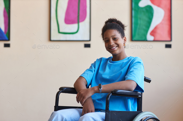 Black teenage girl with disability smiling at camera visiting art gallery