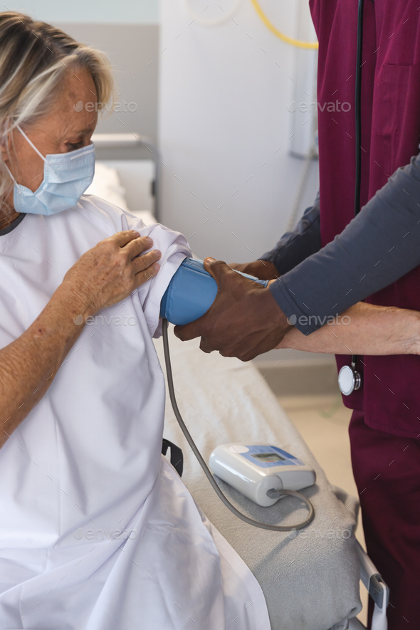 African american doctor measuring blood pressure of senior caucasian