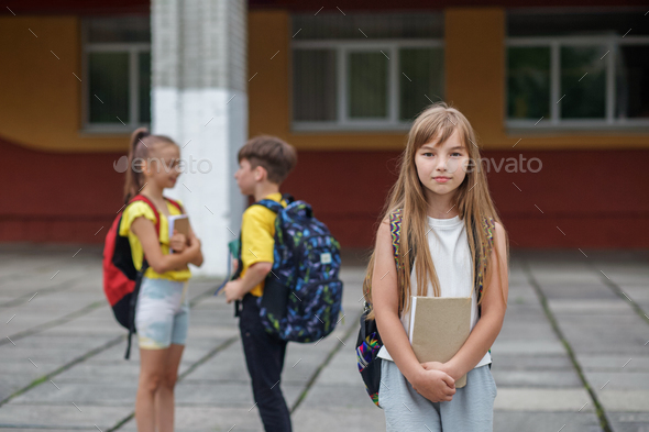 Schoolgirl with book and backpack outdoor. Back to school. Beginning of school lessons.