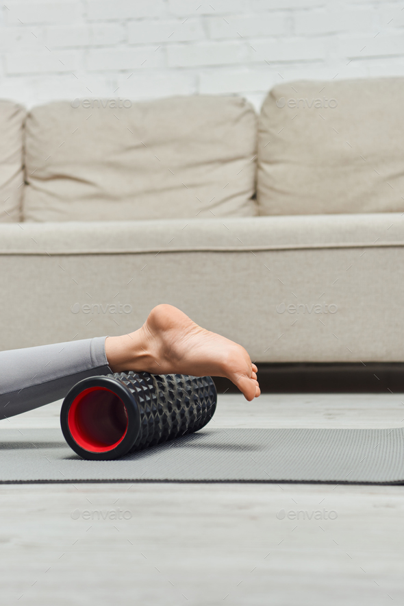 Young brunette woman in activewear holding modern roller massager for lymphatic  drainage Stock Photo by LightFieldStudios