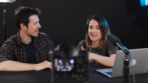 Delighted young bloggers smiling and pointing at camera while filming vlog in studio alt