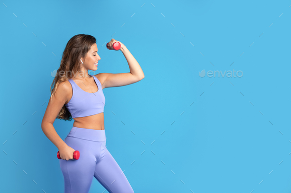 Positive energy slim young caucasian lady in sportswear doing exercises with hand dumbbells, look at