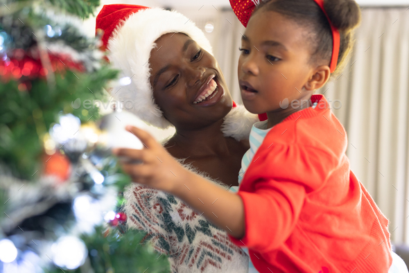 Mom and daughter decorate the Christmas tree Stock Photo by