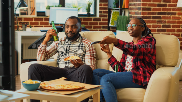 African american partners eating pizza slices at home