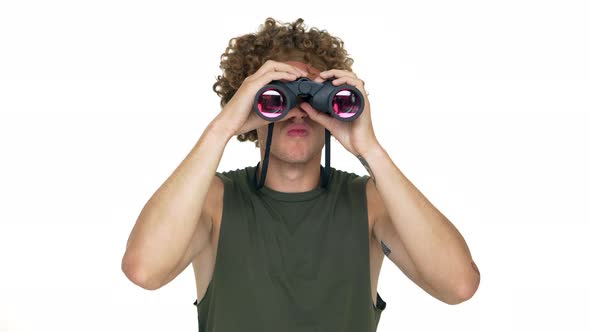 Portrait of Curious Guy with Curly Hair in Green Muscle Shirt Spying Using Binoculars Finding alt