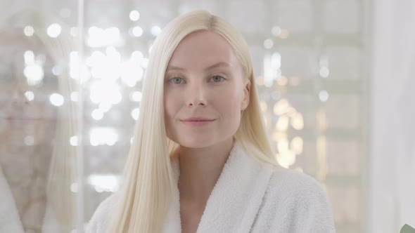 Young Caucasian Woman With Long Blond Hair Wearing a Bath Towel Looking at Camera in a Bright alt