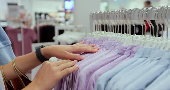 Girl Shopaholic Looks on the Hanger Fashionable Clothes in the Clothes Shop and Fashion Boutique