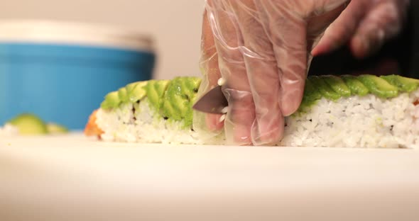 Slicing A Delicious And Healthy Sushi Rolls With Ripe Avocado And Fried Shrimps. - close up shot alt