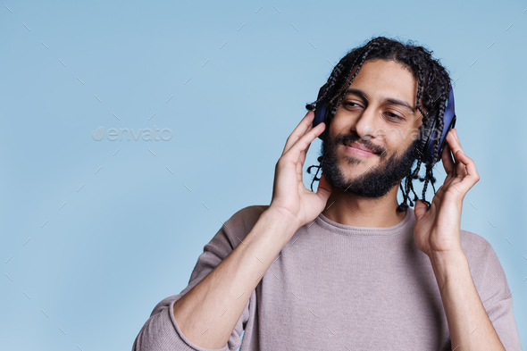 Smiling young man listen to music in modern wireless headphones