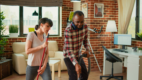 Diverse life partners dancing and sweeping dust off floors