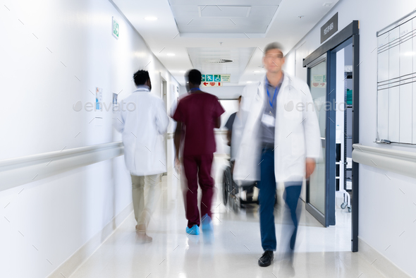 Blurred motion of diverse doctors and medical staff in busy hospital corridor