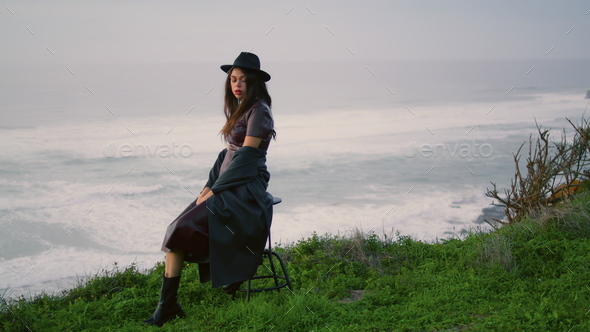 Silhouette stylish model beach sitting on chair. Woman posing at gray ...