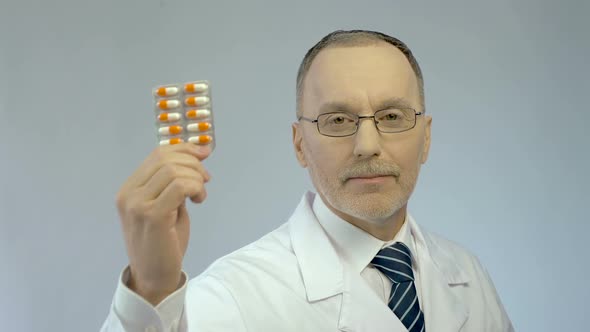 Experienced Doctor Showing Pack of Capsules for Camera, Pharmaceutical Industry alt