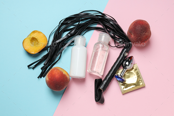 Lubricant with a whip, a peach and a condom on a blue-pink background
