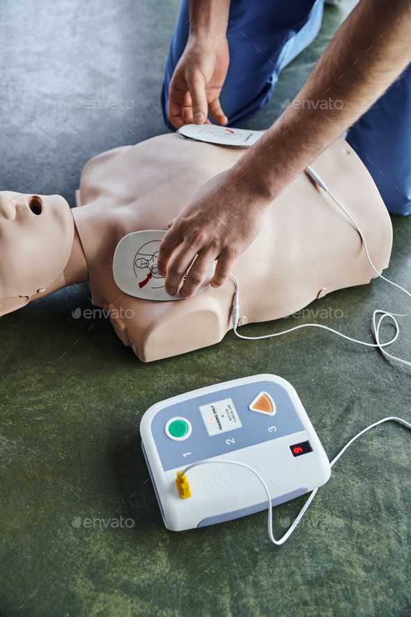 cardiac resuscitation techniques, partial view of professional paramedic applying defibrillator