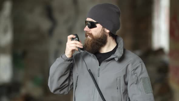 Seriouslooking Bearded Man in Sunglasses Using Walkie Talkie alt