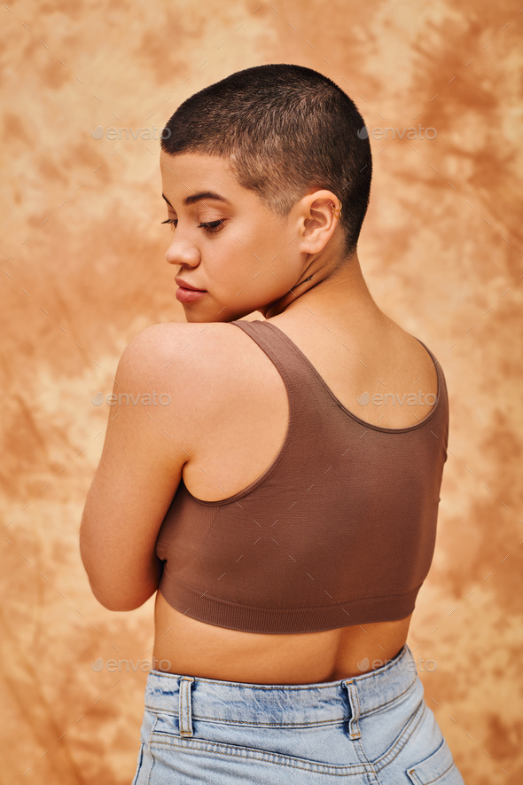 natural beauty, self-esteem, young woman with short hair posing on mottled beige background,