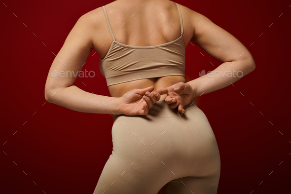 body positive, self-esteem, back view of young woman posing on burgundy background, dark red, curvy