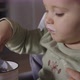 Closeup Portrait of a Baby Girl Eating Yogurt in the Kitchen - VideoHive Item for Sale