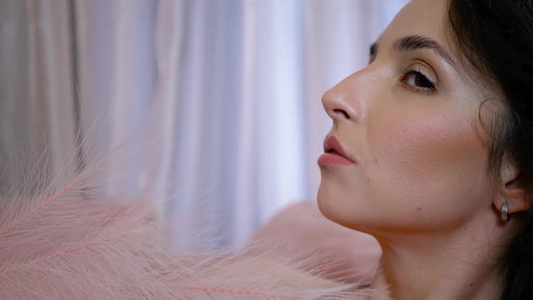 Romantic Woman in Pink Clothes is Lying on the Sofa with Pink Feather alt