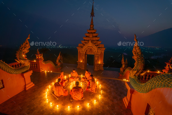 Group of young and senior monk sit in a circle with several lighting candle surround - Stock Photo - Images