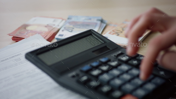 Hands pressing numbers calculator counting money expenses in office close up.