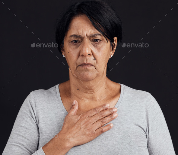 Fear, senior and a woman with a heart attack on a black background with healthcare anxiety. Emergen
