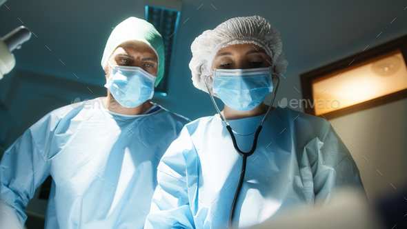 Doctor and nurse lay a surgical drape over the patient