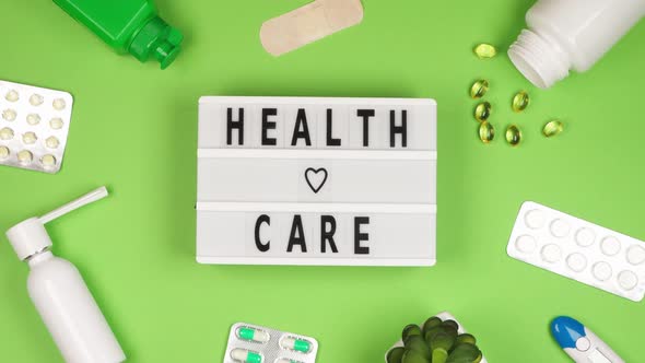 The inscription Health care on a white board on a green background surrounded by many different pill