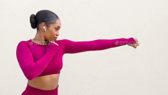 Strong athletic young black woman doing kick on white Stock Photo