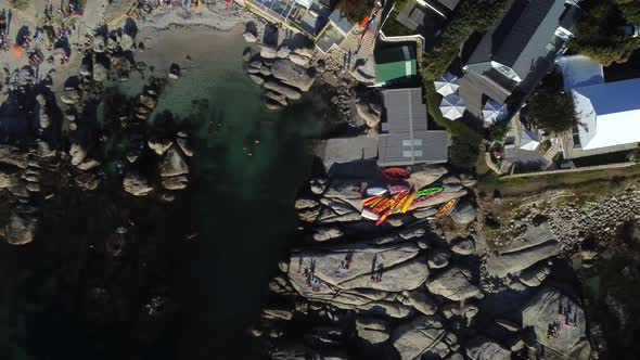 Birds eye drone shot of Bakoven beach in Camps Bay, Cape Town - drone is ascending over some stored alt