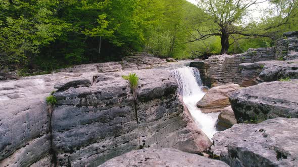 Top View of Rocky Mountain Ledges with a Small Waterfall Drone Shot alt