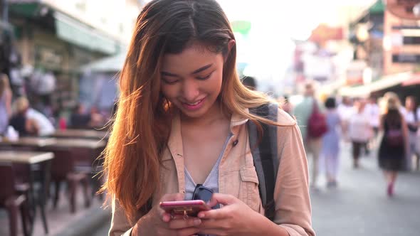 Young Tourist Using a Mobile Phone in Street Market alt